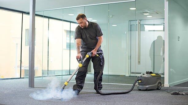 Picture of a man using a steam cleaner.